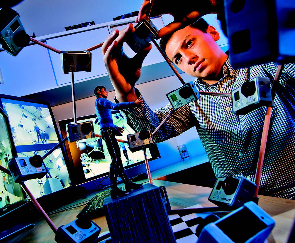 Person working with multiple cameras and monitors, adjusting a 3D motion capture setup.