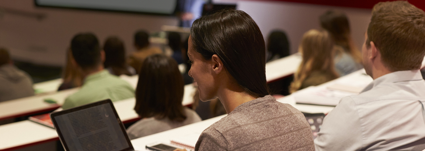 Adult female student using laptop computer at a university lecture.
