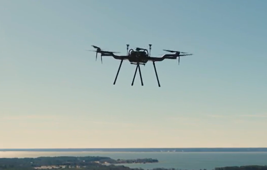 Photo of a drone in the air, above water.